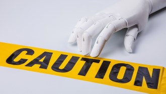 A hand manikin rests on a strip of yellow plastic caution tape, to highlight the need to proceed with caution when using or implementing Generative Artificial Intelligence