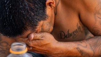 A closeup of a man splashing water on his face